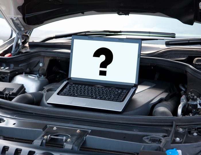 Laptop with question mark on screen inside car engine bay.