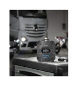 A portable black walkie-talkie device on a table with a blurred truck background.
